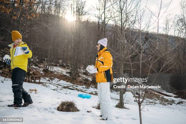 mother and son having fun on snow - melting snowball stock pictures, royalty-free photos & images