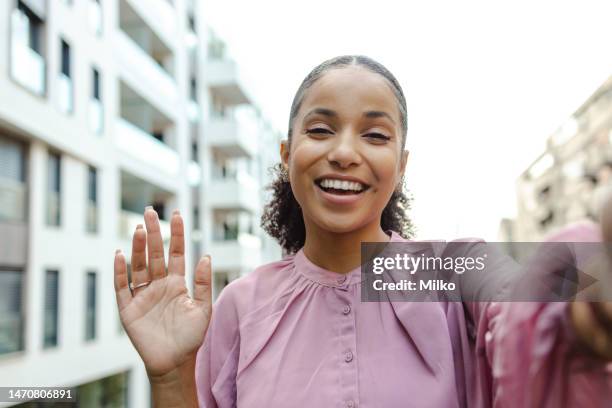 portrait of a latin woman on a video call - female waving on street stock pictures, royalty-free photos & images