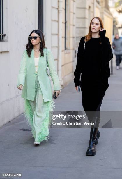 April Hennig mint green blazer, pants & Tiernan Cowling wears black dress at Maison de l’Amérique latine on March 02, 2023 in Paris, France.