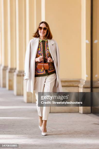 Influencer and style icon Annette Weber, wearing a multicolored paisley silk blouse by Peter Hahn, a white coat by Uta Raasch, white pants by...