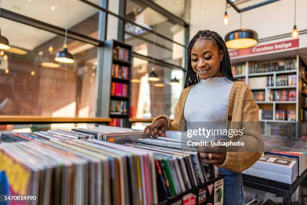 giovane bella donna in un negozio di vinile che sceglie i dischi. - the life picture collection foto e immagini stock