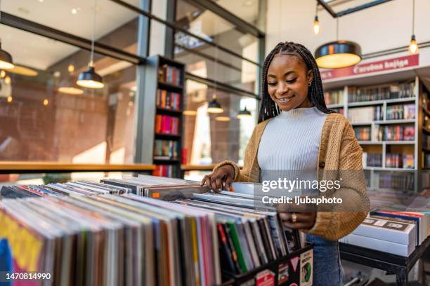 young beautiful woman in a vinyl store choosing records. - loja de música imagens e fotografias de stock