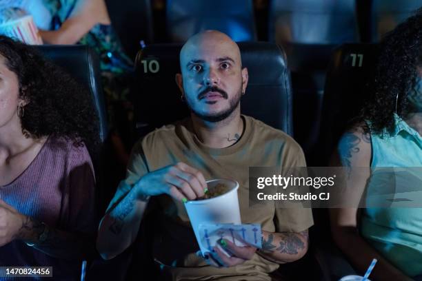 un jeune homme effrayé pendant un film au cinéma - scary movie theatre photos et images de collection