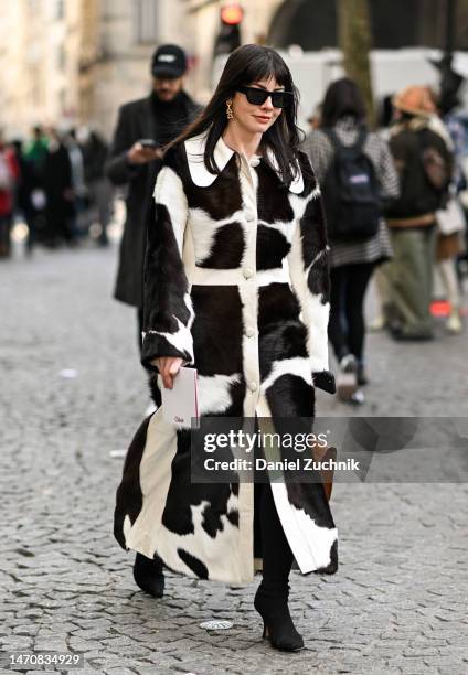 Guest is seen wearing a black and white print faux fur coat and brown Chloe bag, black sunglasses and gold hoop earrings outside the Chloe show...