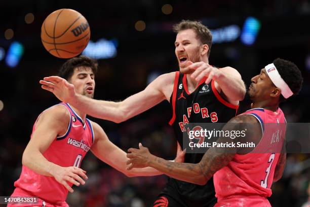 Jakob Poeltl of the Toronto Raptors attempts to grab a loose ball in front of Deni Avdija and Bradley Beal of the Washington Wizards during the first...