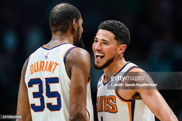 Kevin Durant celebrates with Devin Booker of the Phoenix Suns in the fourth quarter during their game against the Charlotte Hornets at Spectrum...