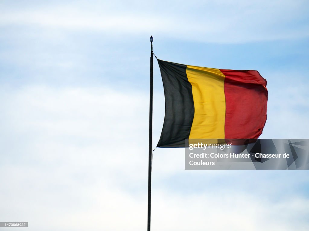 The national flag of belgium flutters in the winds on its mast in Brussels, Belgium