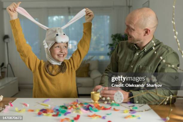 man and his smiling daughter with bunny ears decorate eggs for easter at home - easter bunny mask stockfoto's en -beelden