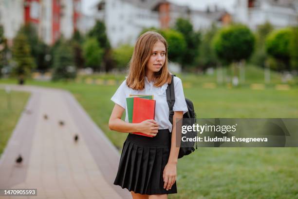 teen girl holding books and posing in the city. back to school - 12 year old in skirt stock pictures, royalty-free photos & images