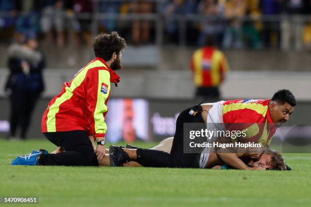 Pitch invader is chased down by security during the round one NRL match between the New Zealand Warriors and Newcastle Knights at Sky Stadium on...