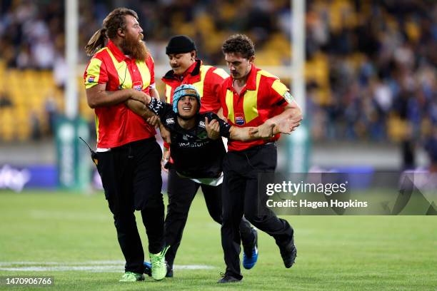 Pitch invader is taken off by security during the round one NRL match between the New Zealand Warriors and Newcastle Knights at Sky Stadium on March...