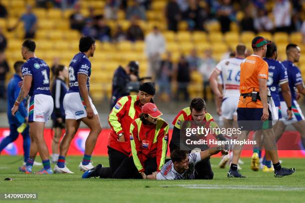 Pitch invader is chased down by security during the round one NRL match between the New Zealand Warriors and Newcastle Knights at Sky Stadium on...