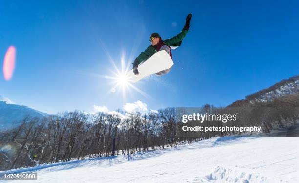 snowboarder doing a jump on a sunny day - freestyle snowboarding imagens e fotografias de stock