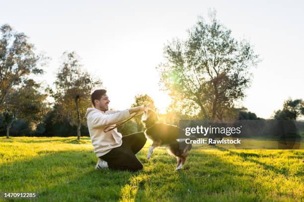 man laughing while playing with his dog in the park - prairie dog photos et images de collection