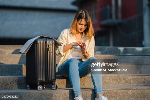 junge asiatische frau alleinreisende sitzt auf treppen mit koffer uns leere brieftasche während der besorgten reise auf der reise. städtischer verkehr und reisen. - lost money stock-fotos und bilder
