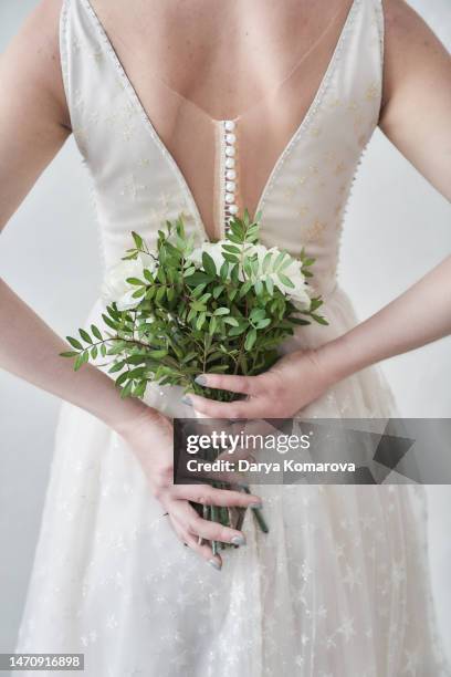 beautiful young woman in a retro dress with a bouquet of white flowers behind her back, unrecognisable person for book cover design or for an invitation wedding card with copy space. design element for your ads. - white dress back stock pictures, royalty-free photos & images