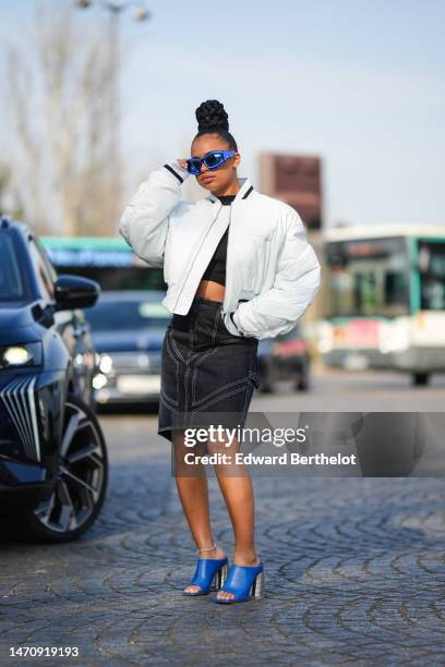 Guest wears blue metallic sunglasses from Off-Whit, a black high neck / cropped top from from Off-White, a white shiny leather crocodile embossed...