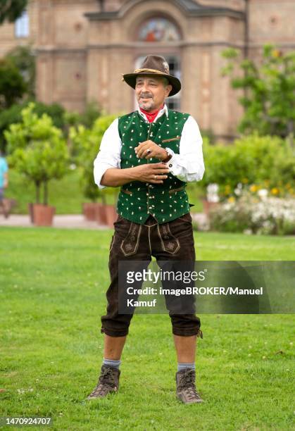 man in bavarian traditional costume with hat standing on green lawn, karlsruhe, germany - headwear stock-fotos und bilder