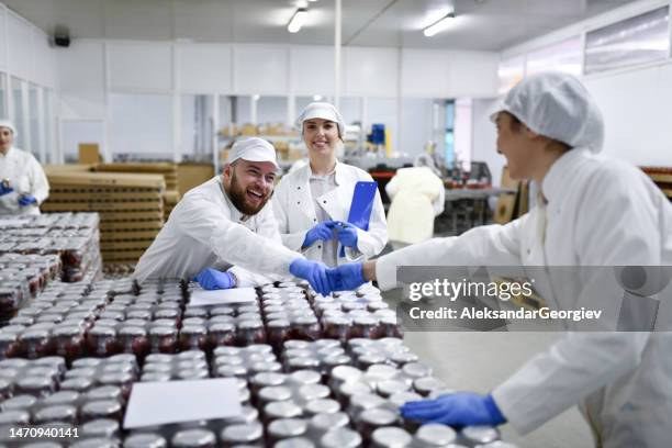 lächelnde arbeiter in der pfefferverarbeitungsanlage schütteln hände und bereiten sich darauf vor, gläser in den lagerraum zu bringen - nahrungsmittelfabrik stock-fotos und bilder