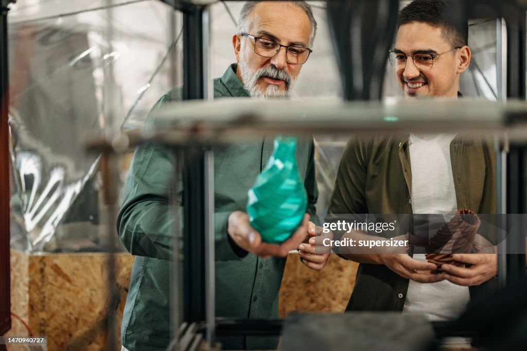 Shot through 3d printer of senior professor working with Caucasian student