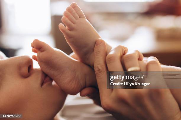 close up of mother kisses her baby's feet. - baby skin fotografías e imágenes de stock