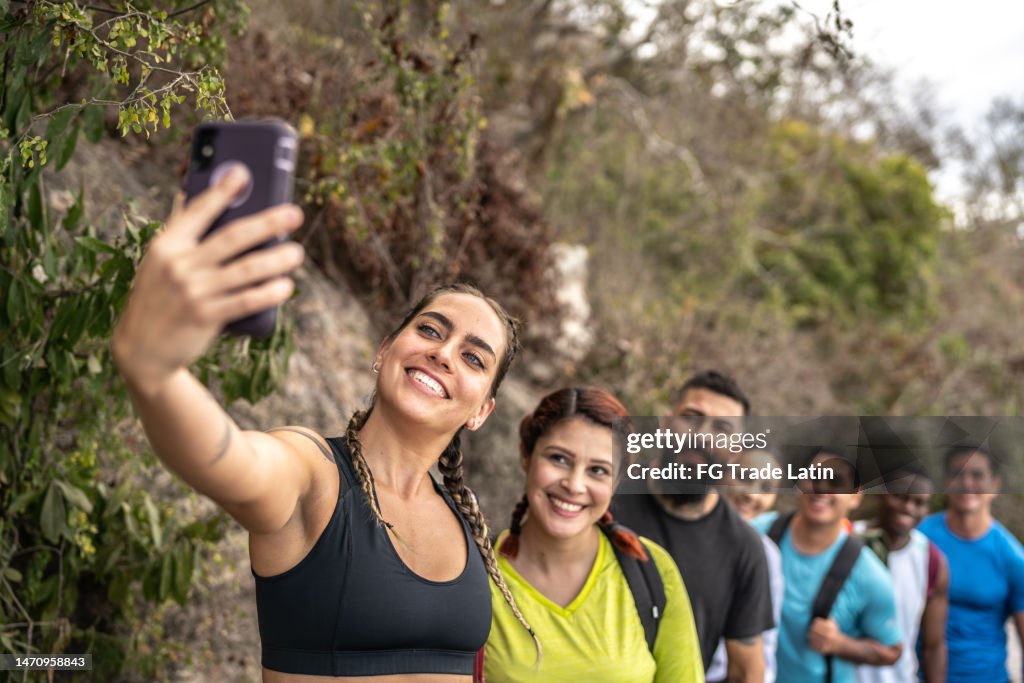 Mujer adulta mediana tomando una selfie con sus amigos durante una caminata al aire libre