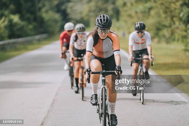 female asian chinese cyclist leading in cycling event in morning rural scene - fietsevenement stockfoto's en -beelden