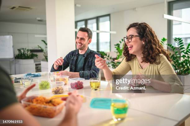 colpo di vita in su dei dipendenti del marketing caucasico che ridono mentre mangiano - pausa pranzo foto e immagini stock