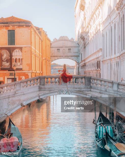 a young woman in a red dress enjoys eating pizza on the bridge of sighs in st. mark's square in venice, italy - red dress stockfoto's en -beelden