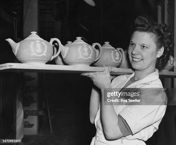Wedgwood pottery worker Frances Pitt carries a tray of Wedgwood Blue teapots pieces, each adorned with the head of Elizabeth II, as they head for the...