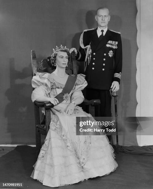 Waxwork figures of British Royal Queen Elizabeth II seated beside a figure of her husband, Prince Philip, Duke of Edinburgh, who stands in uniform,...