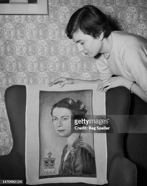 Woman inspects a tapestry covering for a chair with a depiction of Elizabeth II at an exhibition of approved Coronation souvenirs, ahead of the...