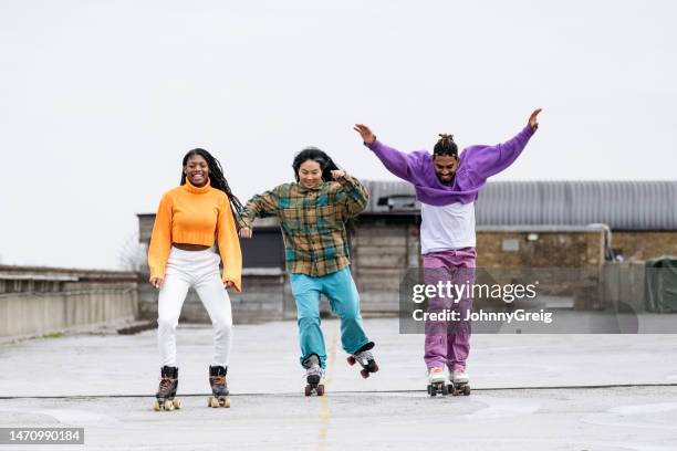 des patineurs à roulettes noirs et asiatiques s’amusent sur le toit - femme sportive photos et images de collection