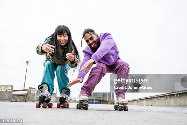 action portrait of roller skating partners - facing front stock pictures, royalty-free photos & images