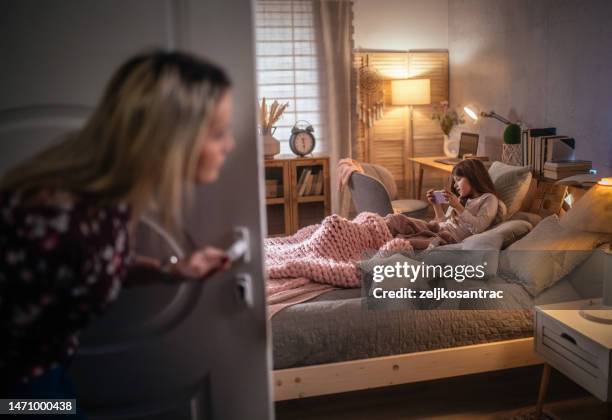 mama spioniert ihre tochter aus, während sie das telefon im schlafzimmer benutzt - girls in bedroom stock-fotos und bilder