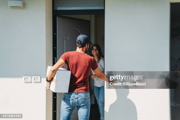 a delivery man is standing in front of the customer's entrance door - postbode stockfoto's en -beelden