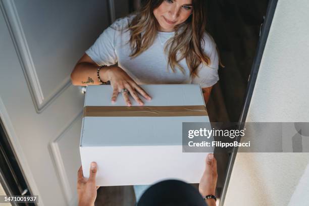delivery man is giving a box to a woman - unusual-angle stock pictures, royalty-free photos & images