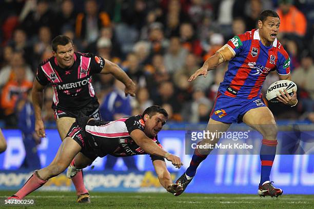 Timana Tahu of the Knights makes a break on his way to scoring a try during the round 16 NRL match between the Newcastle Knights and the Wests Tigers...