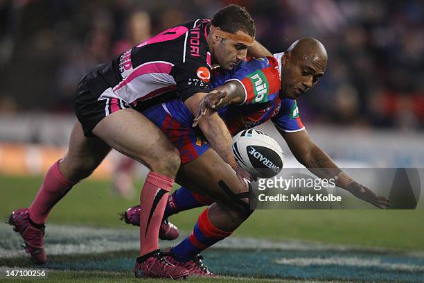 Robbie Farah of the Tigers tackles Akuila Uate of the Knights as he loses the ball during the round 16 NRL match between the Newcastle Knights and...