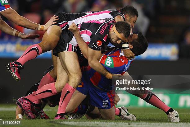 Benji Marshall and Robbie Farah of the Tigers tackle Kade Snowden of the Knights during the round 16 NRL match between the Newcastle Knights and the...