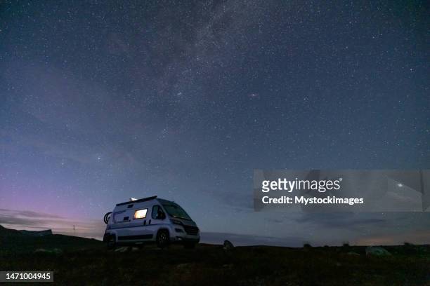 a camper van illuminated from inside standing on a high plateau, starry night without moon at night. - car interior no people stock pictures, royalty-free photos & images