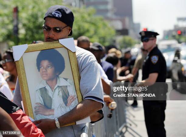 Michael Townes holds a portrait of a young Michael Jackson as he and other people wait in line for a public memorial for pop star Michael Jackson...
