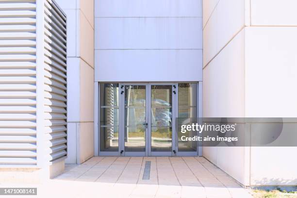 front view of the closed glass doors of a building facade with the reflection of a standing person photographing. - apartment front door stock pictures, royalty-free photos & images