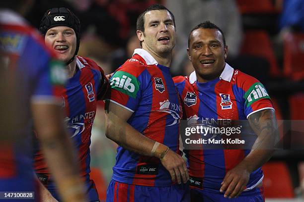 Joel Edwards, James McManus and Neville Costigan of the Knights celebrate a try scored by McManus during the round 16 NRL match between the Newcastle...