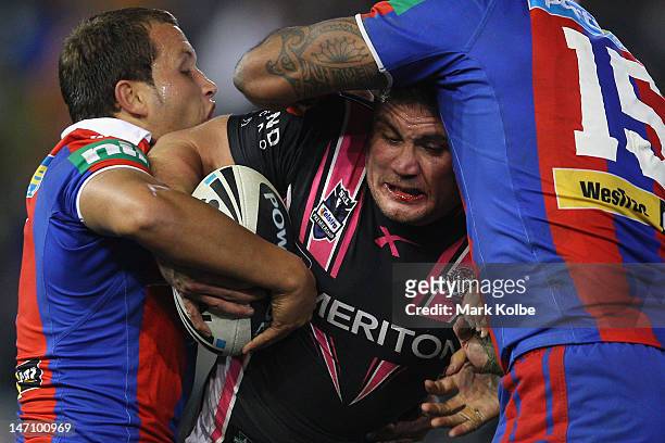 Chris Heighington of the Tigers is tackled during the round 16 NRL match between the Newcastle Knights and the Wests Tigers at Hunter Stadium on June...