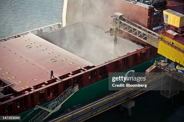 An employee walks across the deck of the "African Wind" cargo ship as grain is loaded into a storage chamber in the hull, at Lecureur SA's cereal...