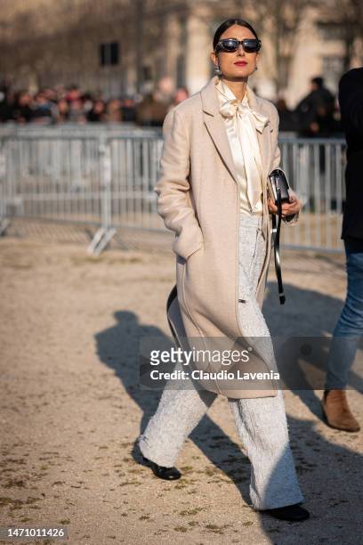 Julia Haghjoo wears a cream satin blouse, cream pants, beige coat, outside Givenchy, during Paris Fashion Week - Womenswear Fall Winter 2023 2024, on...