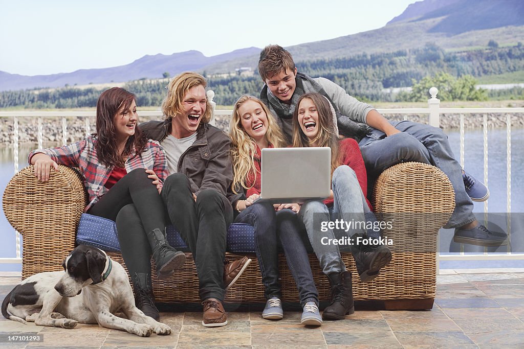 Teens sharing funny moment on laptop.