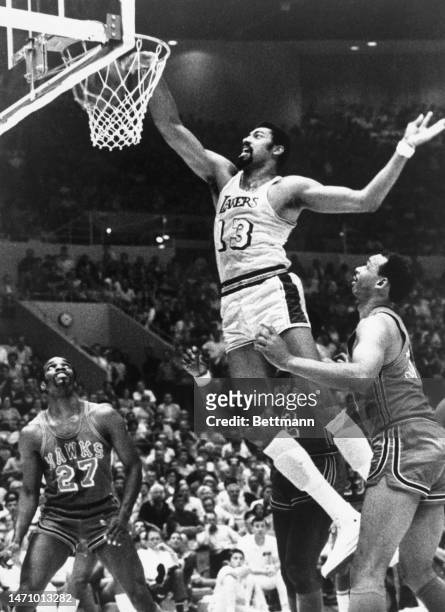 The Los Angeles Lakers' Wilt Chamberlain , lays into the basket with a one-handed dunk to score two points in the first period. Joe Caldwell , and...