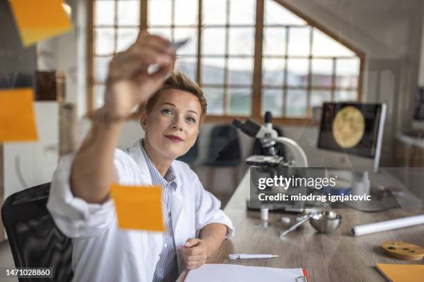 female scientist working in office - sticky-notes-covering-computer-monitor stock pictures, royalty-free photos & images
